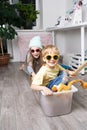 Children have fun and ride in a white plastic box. The room is a mess. Royalty Free Stock Photo