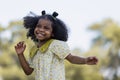 African black child with curly hair is jumping happily in the water spray at outdoor