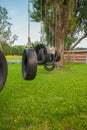 Children having fun holding hands with parents at park with tire swing in foreground and sunlight coming through trees. Having Royalty Free Stock Photo