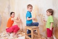 Children help mother remove old wallpapers from wa