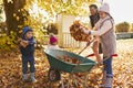 Children Helping Father To Collect Autumn Leaves In Garden Royalty Free Stock Photo