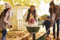 Children Helping Parents To Collect Autumn Leaves In Garden Royalty Free Stock Photo