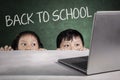 Children hiding with back to school text on board