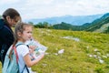 Children hiking on beautiful summer day in alps mountains Austria resting on rock. Kids look at map mountain peaks in Royalty Free Stock Photo