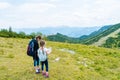 Children hiking on beautiful summer day in alps mountains Austria resting on rock. Kids look at map mountain peaks in Royalty Free Stock Photo