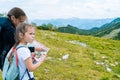 Children hiking on beautiful summer day in alps mountains Austria resting on rock. Kids look at map mountain peaks in valley. Royalty Free Stock Photo