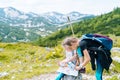 Children hiking on beautiful summer day in alps mountains Austria resting on rock. Kids look at map mountain peaks in Royalty Free Stock Photo