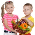 Children hold a basket with vegetables