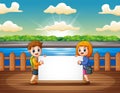 Children holding blank sign at the wooden pier Royalty Free Stock Photo