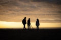 Children on holiday vacation silhouetted as they are treasure detecting at sunset on beach near ocean with metal detector sun