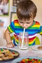 Funny boy eat cookies with round multi-colored sweets m&m and drink milk. Royalty Free Stock Photo