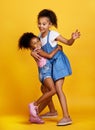 Children, hug and happy sisters in studio dancing with love, care and support of family on yellow background. Cute young Royalty Free Stock Photo