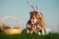 Children hunting easter eggs. Kid boy lying on the grass and finding easter eggs, on sky background with copy space Royalty Free Stock Photo