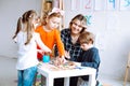 Children with interest play with educational toys on desk sitting on floor. Smiling educator point at empty hole in