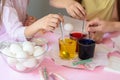 Children interfere with a solution with food coloring in glasses to paint Easter eggs Royalty Free Stock Photo