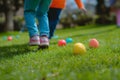 Children on a Joyful Easter Egg Hunt in Sunlit Garden. Kids legs in a park, with colorful eggs dotting the grass on a sunny day. Royalty Free Stock Photo