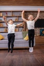 Children jump and dance at home while listening to music on headphones. Having fun. Family concept Royalty Free Stock Photo