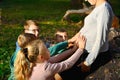 Children keep their hands on the belly of a pregnant mom in the forest on the nature on a background of green grass