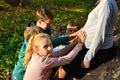 Children keep their hands on the belly of a pregnant mom in the forest on the nature on a background of green grass