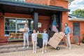 children with keys and parents with cardboard boxes standing at country house moving