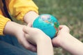 Children kid girl in a yellow raincoat and boy holding globe in a hands outdoor in park or forest. World Earth Day concept. Green Royalty Free Stock Photo