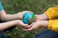 Children kid girl in a yellow raincoat and boy holding globe in a hands outdoor in park or forest. World Earth Day concept. Green Royalty Free Stock Photo