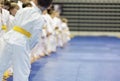 Children in kimono standing in a long line on tatami on martial arts seminar