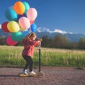 Children learn to ride scooter in a park on sunny summer day. Preschooler boy and girl in safety helmet riding a roller Royalty Free Stock Photo