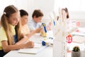 Children learning in class with humanoid robotic hand on foreground