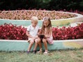 Children learning a digital tablet and sitting in the park. A boy and girl playing in a gadget on a natural background.