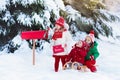 Children with letter to Santa at Christmas mail box in snow