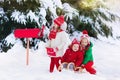 Children with letter to Santa at Christmas mail box in snow