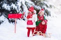 Children with letter to Santa at Christmas mail box in snow