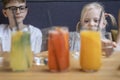 Children look at bright colorful drinks. Glasses with fruit juices and lemonade in front of children