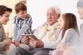 Children looking at grandpa holding a tablet