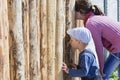 Children are looking through the hole in the fence Royalty Free Stock Photo