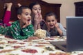 Children looking at laptop with cartoons showing before sleeping in bed. Three children in bed watching a movie on a laptop