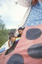 Children looking out of a colorful teepee