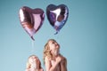 Children, love and sister with heart balloon in studio on blue background for family or party. Birthday, celebration or