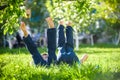 Children lying on green grass in park on a summer day with their legs lifted up to the sky