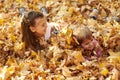 Children are lying and playing on fallen leaves in autumn city park. Royalty Free Stock Photo