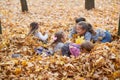 Children are lying and playing on fallen leaves in autumn city park. Royalty Free Stock Photo