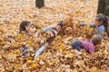 Children are lying and playing on fallen leaves in autumn city park. Royalty Free Stock Photo