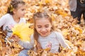 Children are lying and playing on fallen leaves in autumn city park. Royalty Free Stock Photo