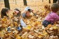 Children are lying and playing on fallen leaves in autumn city park. Royalty Free Stock Photo