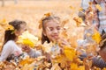 Children are lying and playing on fallen leaves in autumn city park. Royalty Free Stock Photo