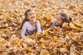 Children are lying and playing on fallen leaves in autumn city park. Royalty Free Stock Photo