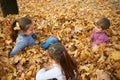 Children are lying and playing on fallen leaves in autumn city park. Royalty Free Stock Photo