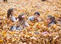 Children are lying and playing on fallen leaves in autumn city park Royalty Free Stock Photo