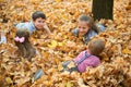 Children are lying and playing on fallen leaves in autumn city park Royalty Free Stock Photo